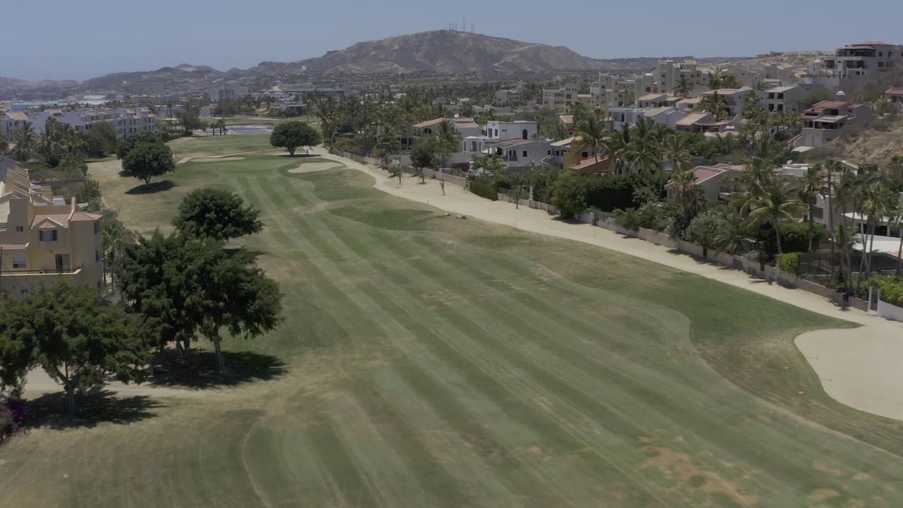 Aerial view over a golf fairway beside homes and palms