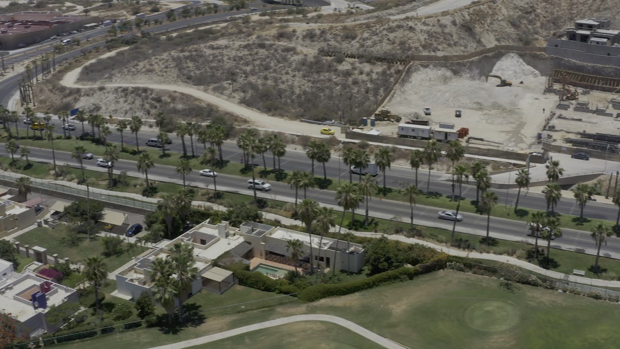 Overhead road with cars, palms, homes, and dry hillside