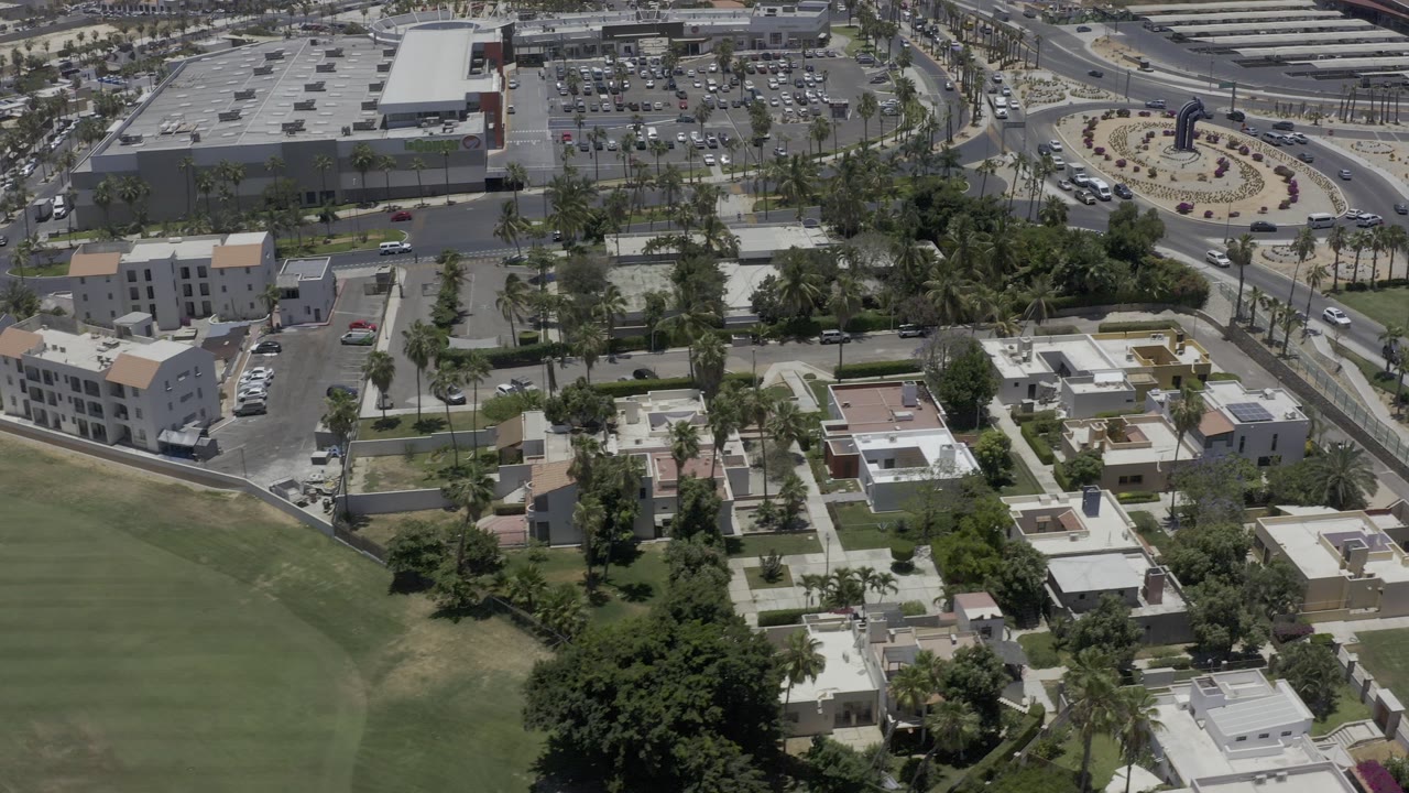 Aerial view of homes, green lawn, roads, and a large parking lot.