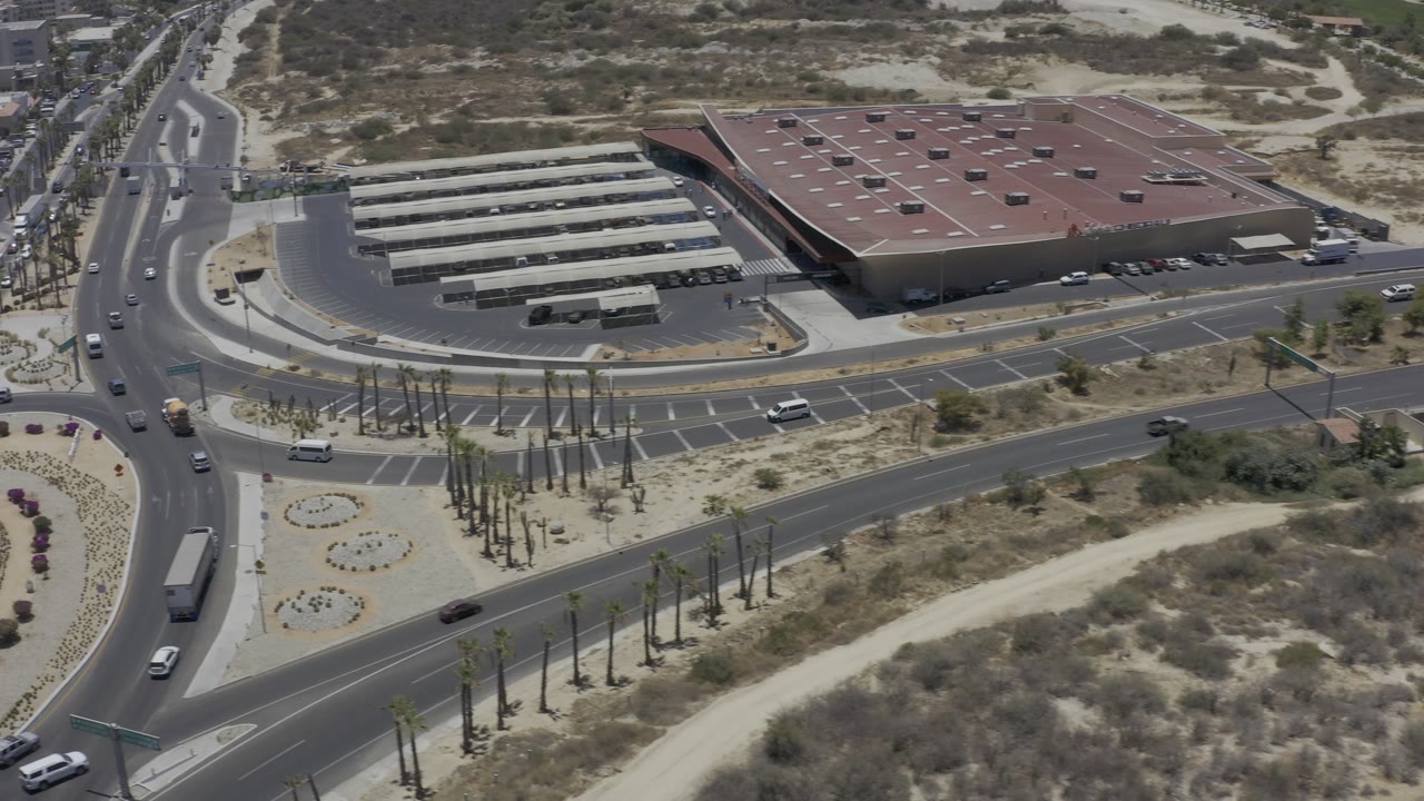 Aerial view of traffic lanes, landscaped median, and red-roofed building.