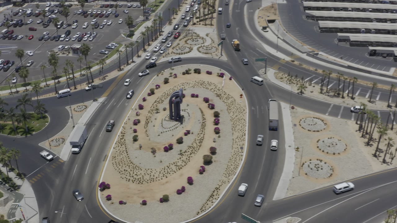 Aerial view of cars moving around a landscaped roundabout and intersecting roads.