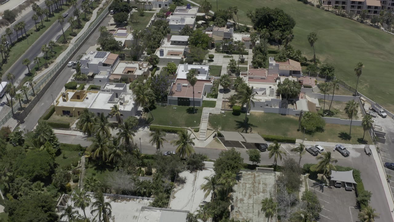Drone view of residential buildings beside a large green area and roads.