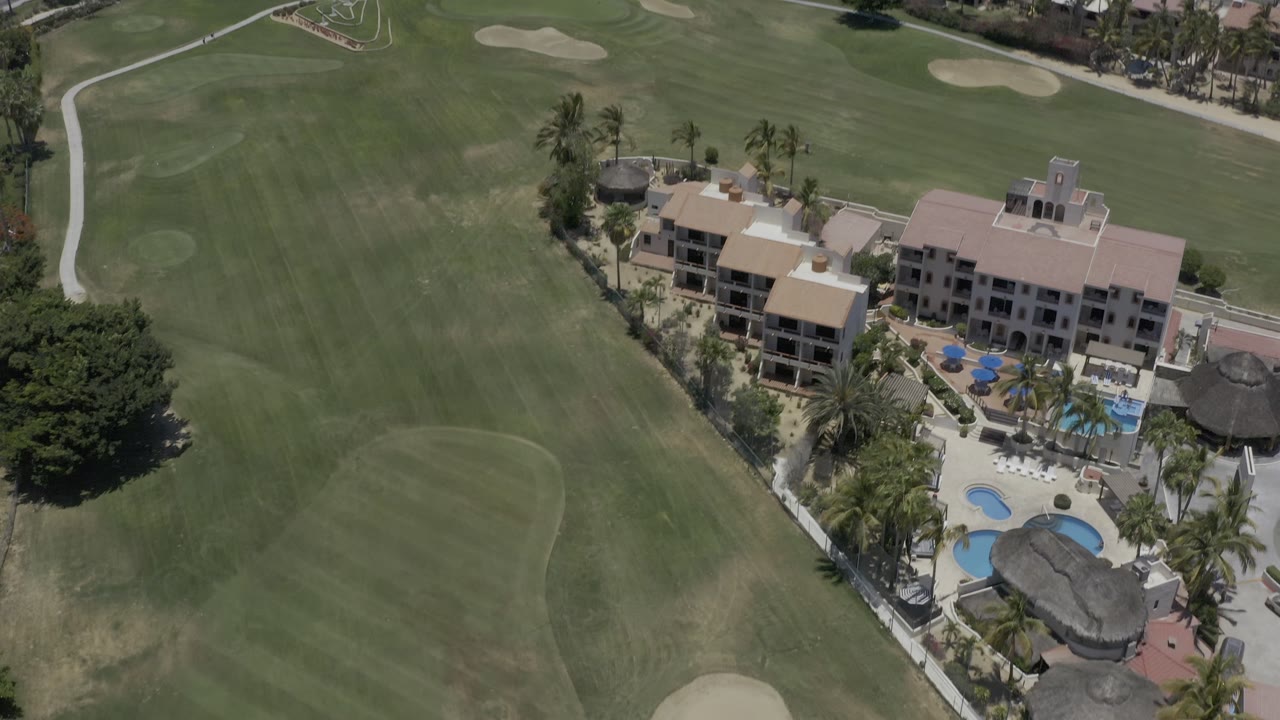 Aerial frame with resort complex at right and open golf course at left.