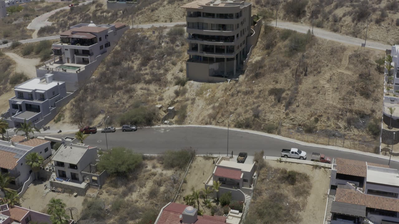 Aerial view of hillside vacation buildings and a curved road