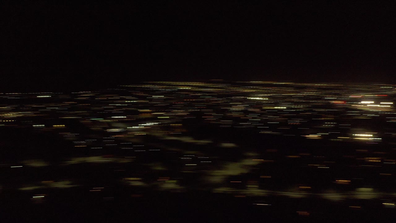 Dark nighttime city view with scattered lights under a black sky.
