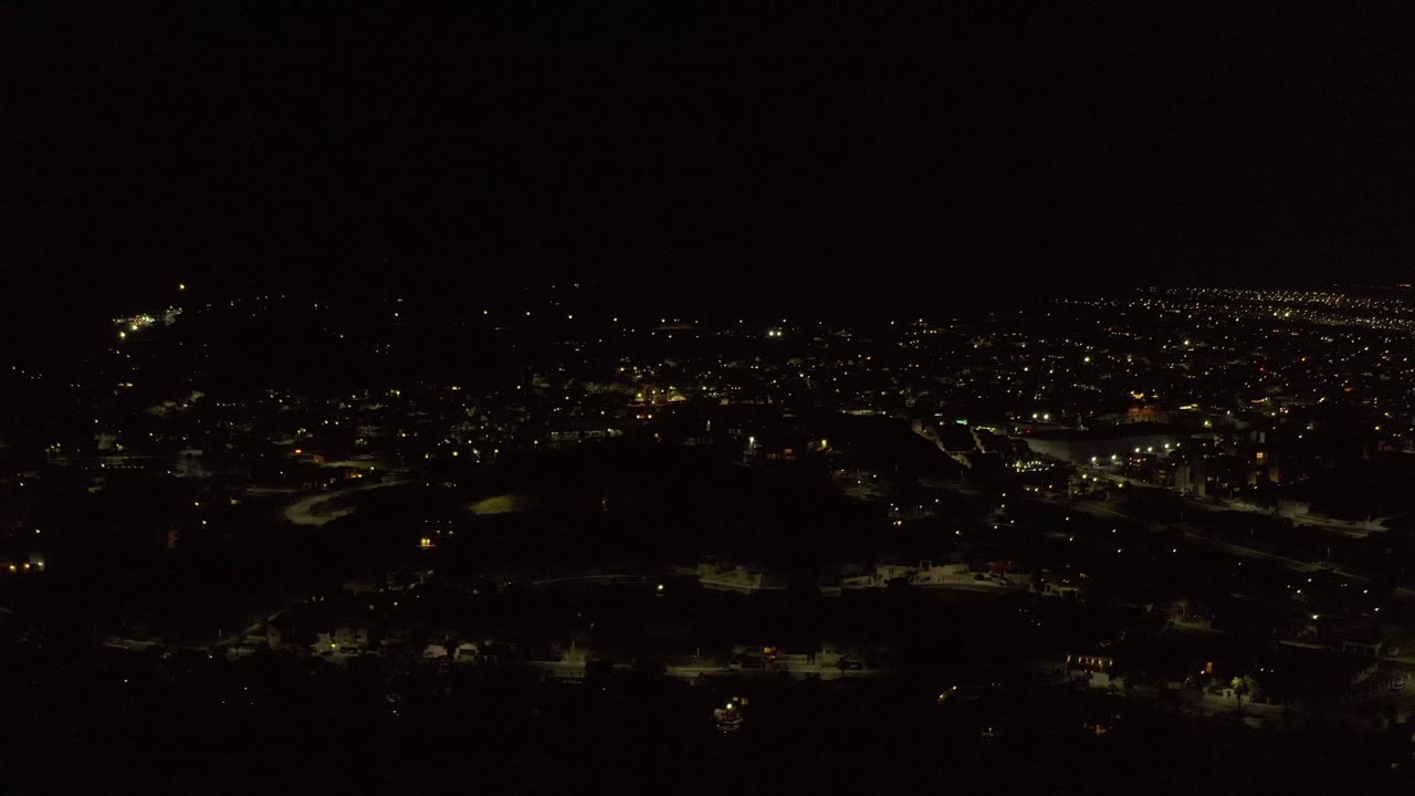 Wide night skyline with roads and scattered lights.