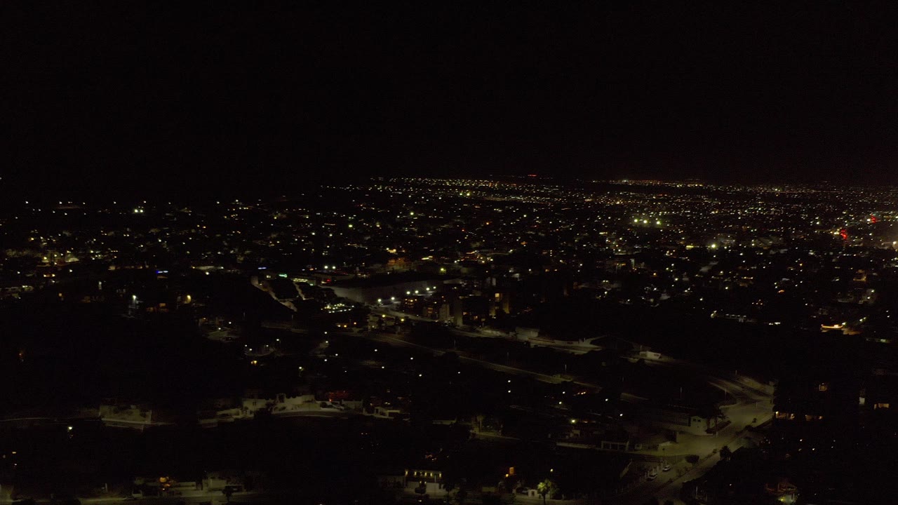 Wide nighttime city view with scattered lights under a dark sky.