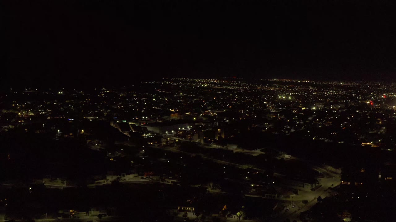 Los Cabos night view one second in, showing a wide spread of warm lights across low urban areas and no visible people.