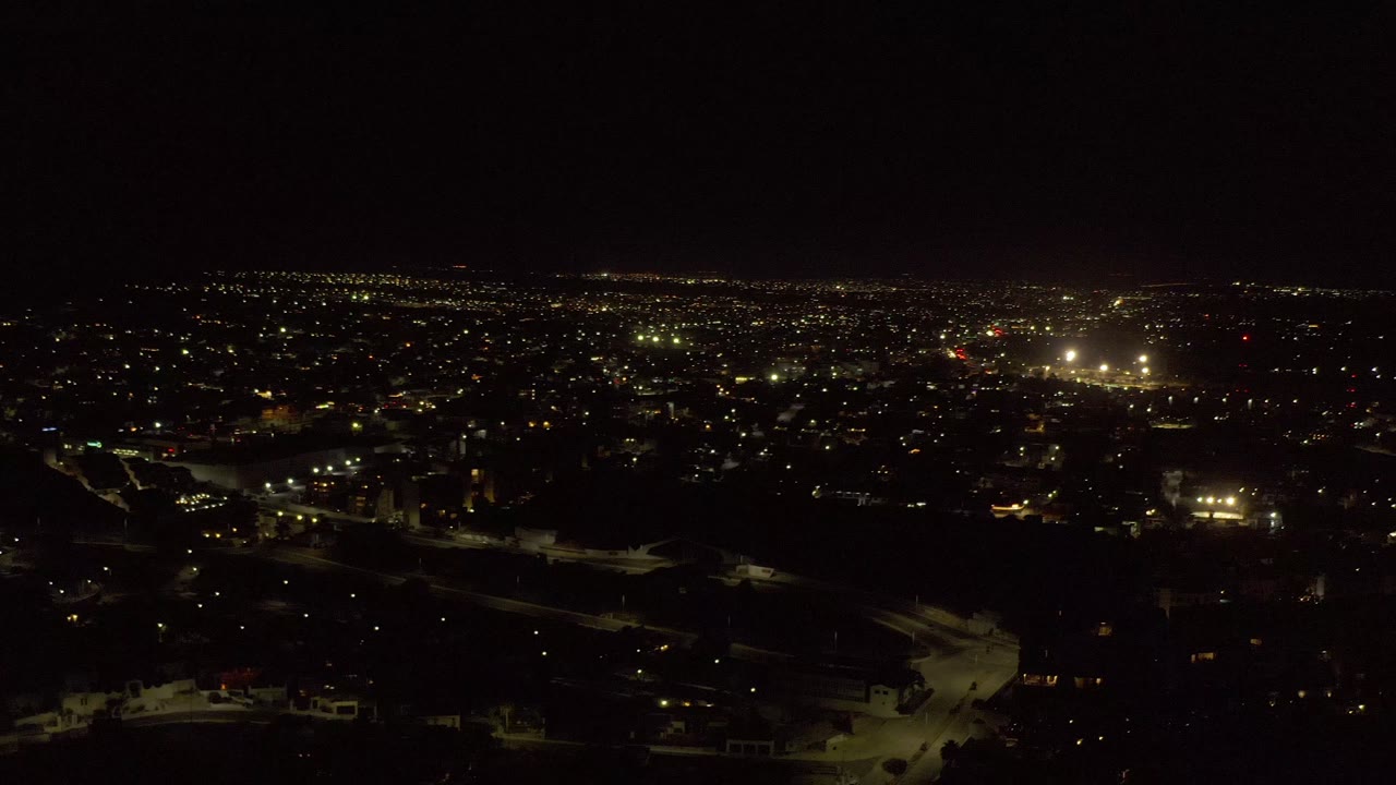 Broad city lights at night with black sky above.