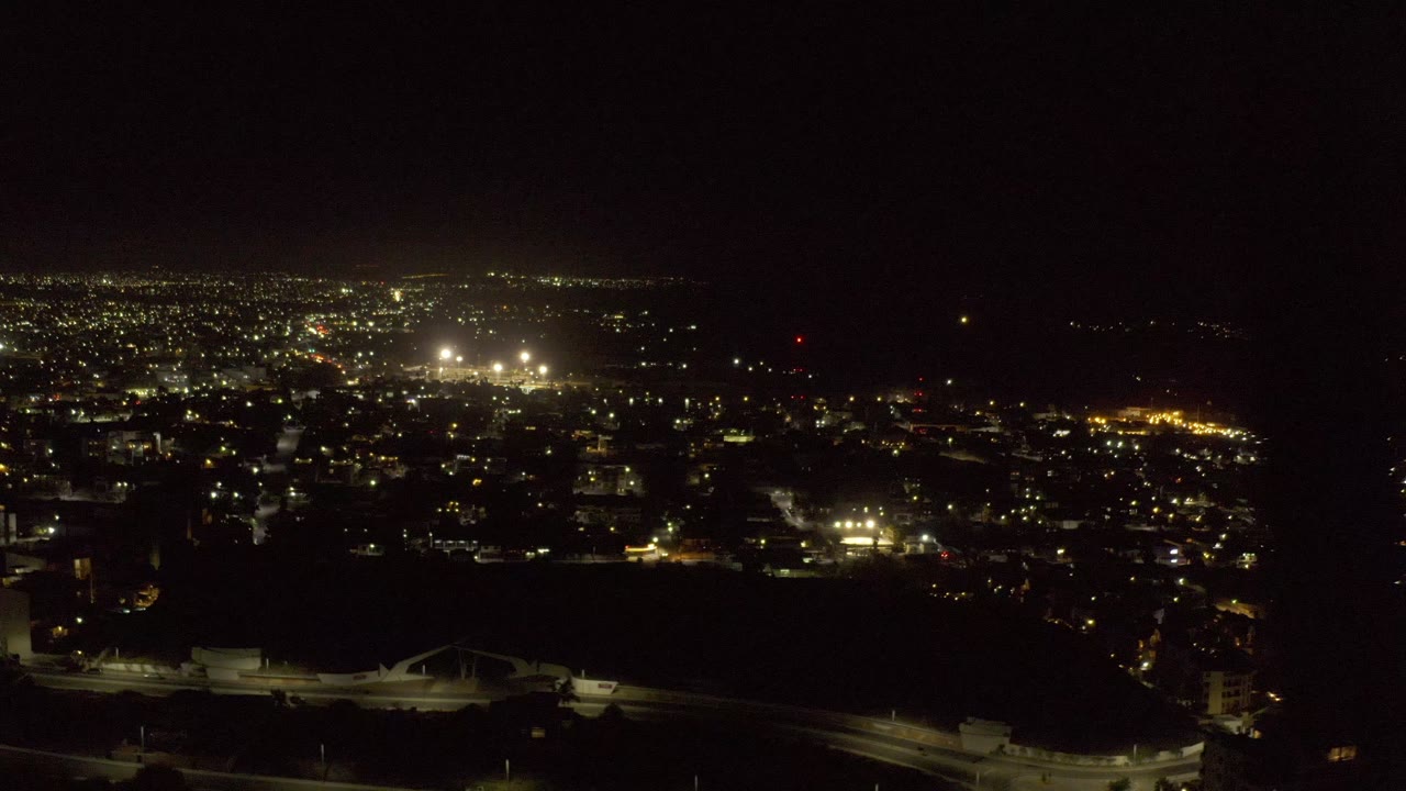 Elevated night view over lit roads and distant city lights