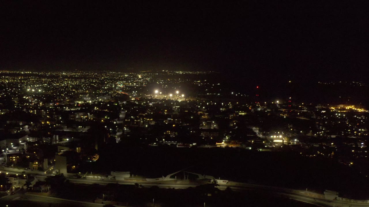 Wide aerial view of illuminated roads and buildings at night.