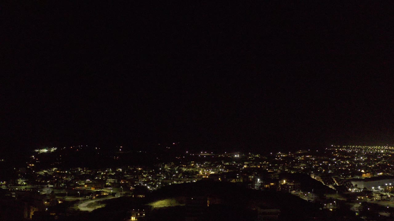 Night aerial view of city lights below a black sky.