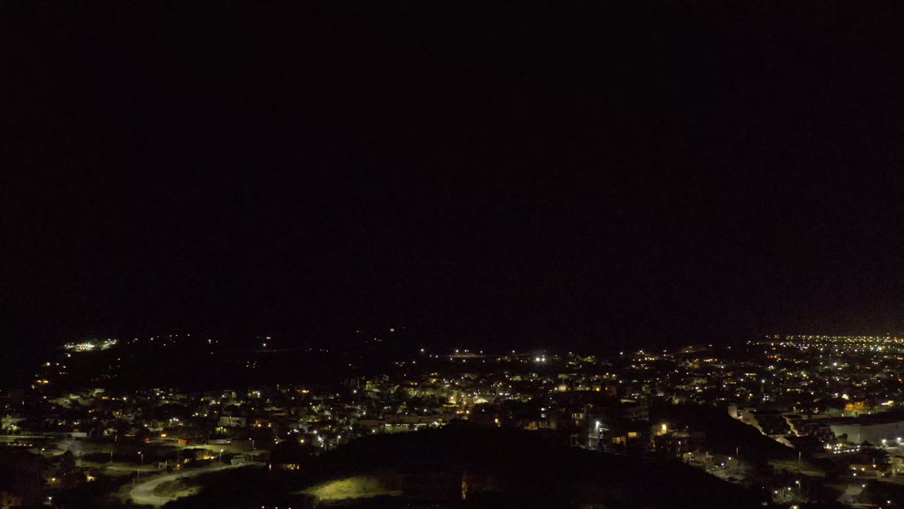 Second frame of the Los Cabos night view with warm lights spread across the midground and a nearly black foreground, with no visible people.
