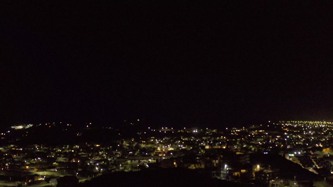 Distant city lights spread across a dark night landscape