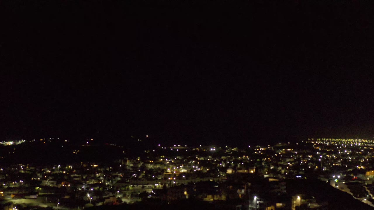 Los Cabos night view with a broad band of lights across the lower frame, dark land in the foreground, and no visible people.