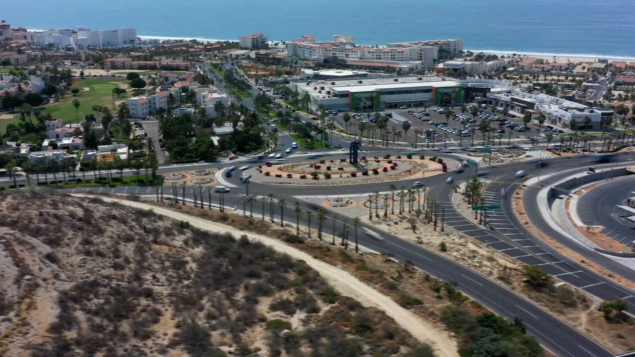Aerial view of a roundabout, roads, buildings, and ocean horizon.