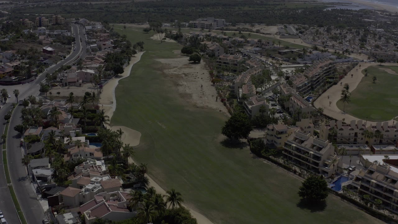 Aerial view of a golf course beside residential streets and homes.
