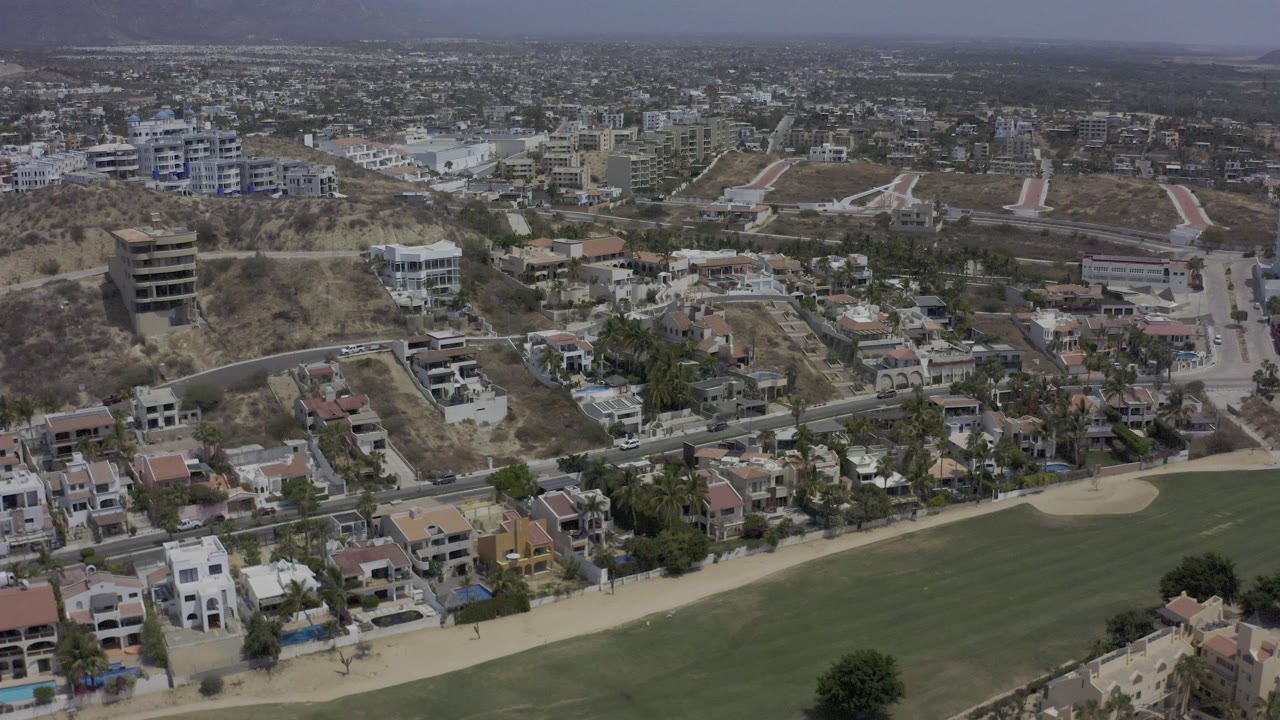 Aerial view of hillside homes, streets, and a golf course edge.
