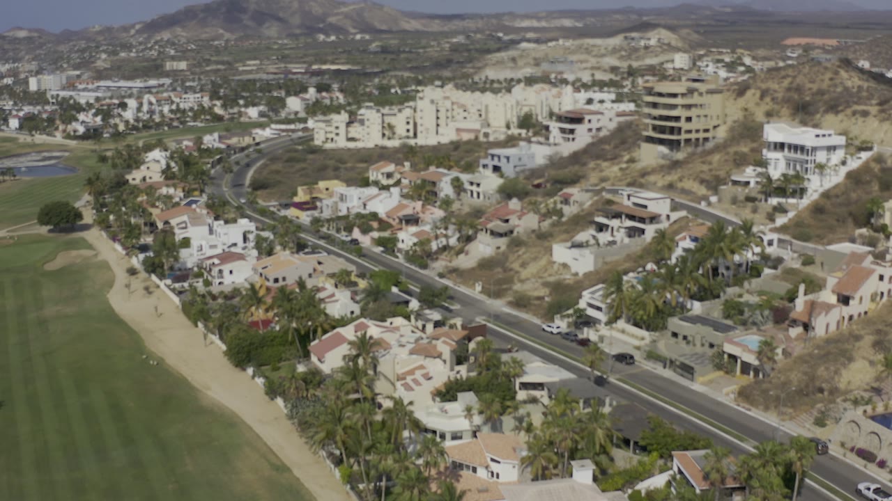 Road and residential area beside a green open field.