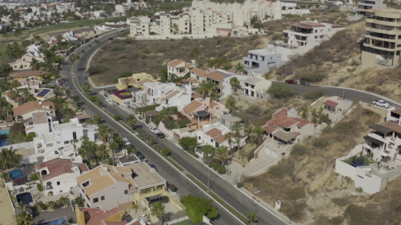 Aerial neighborhood view with villas, road, and apartment buildings.