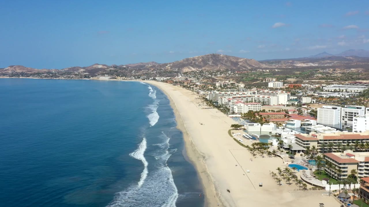 High view of ocean waves approaching a sandy Los Cabos beach.