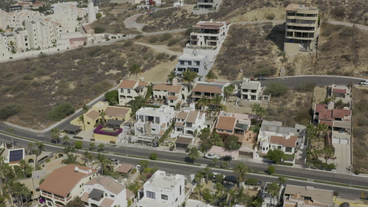 Drone-like view of close-set homes and hillside buildings.