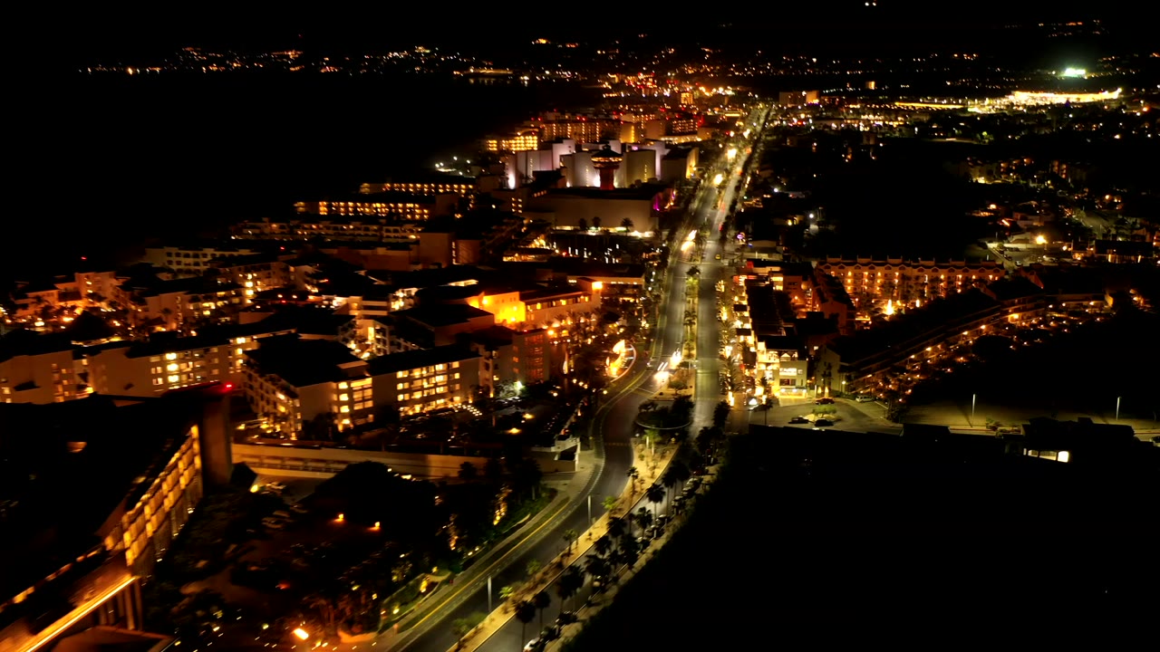 Aerial night view of a lit road through resort buildings.