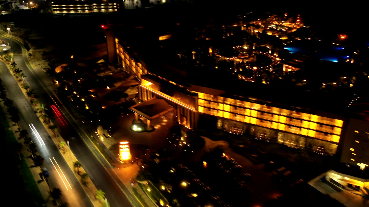 Aerial night view of a warm-lit building beside a road