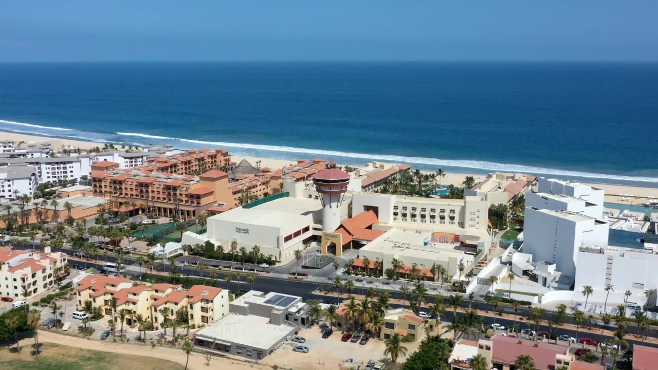 Beachfront district with ocean, surf, road traffic, and rooftops.