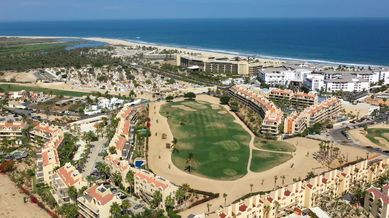 Aerial view of a coastal golf course beside buildings and ocean