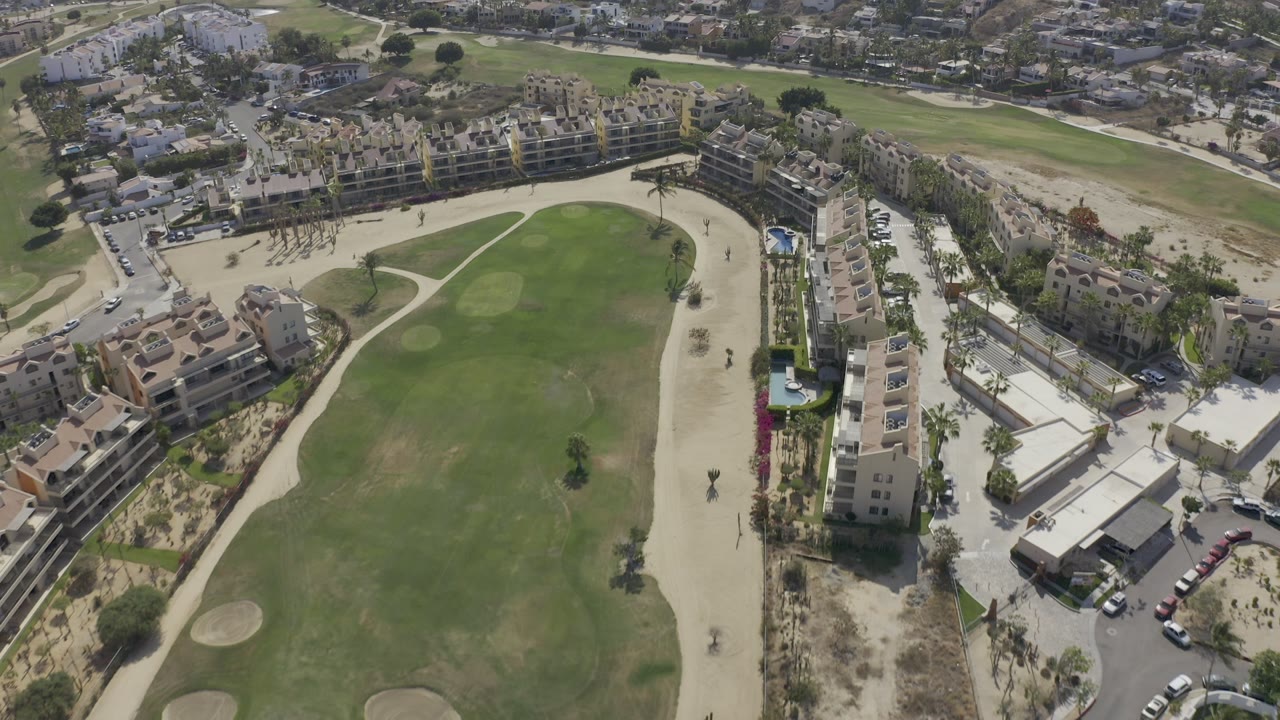 Aerial view of a golf course beside apartment buildings and streets.