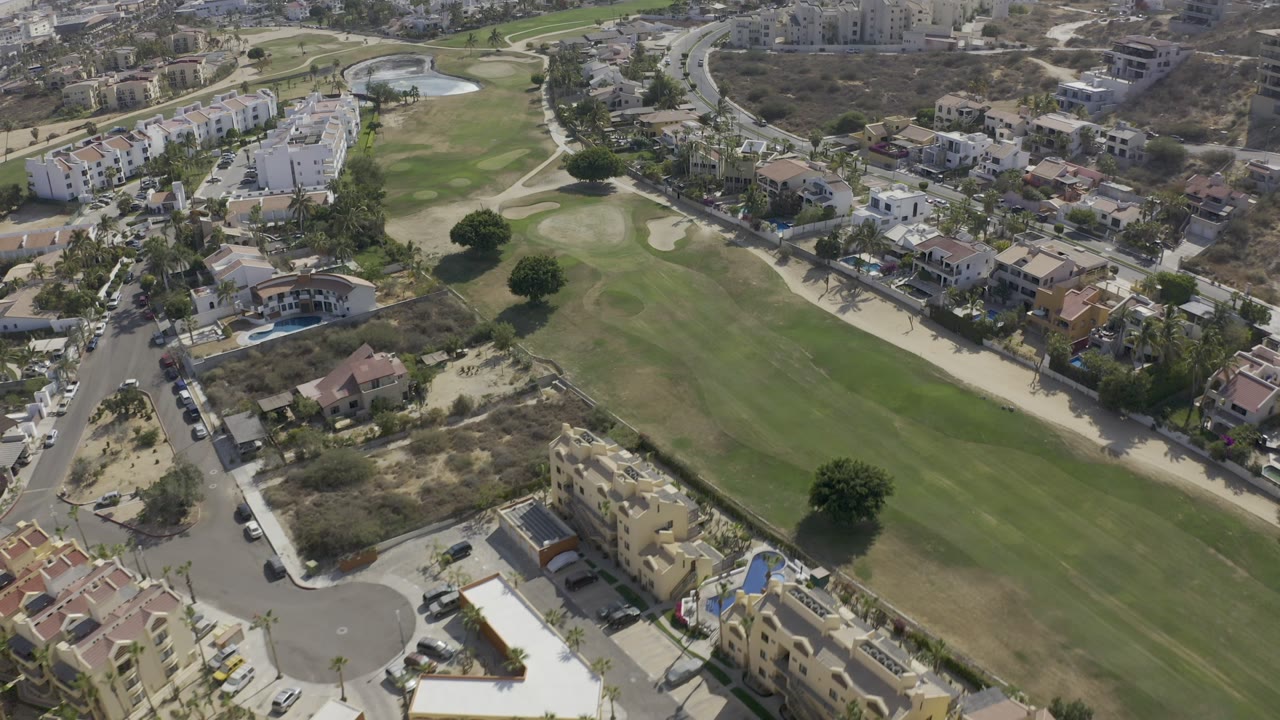 Aerial view of a green fairway bordered by homes and roads.