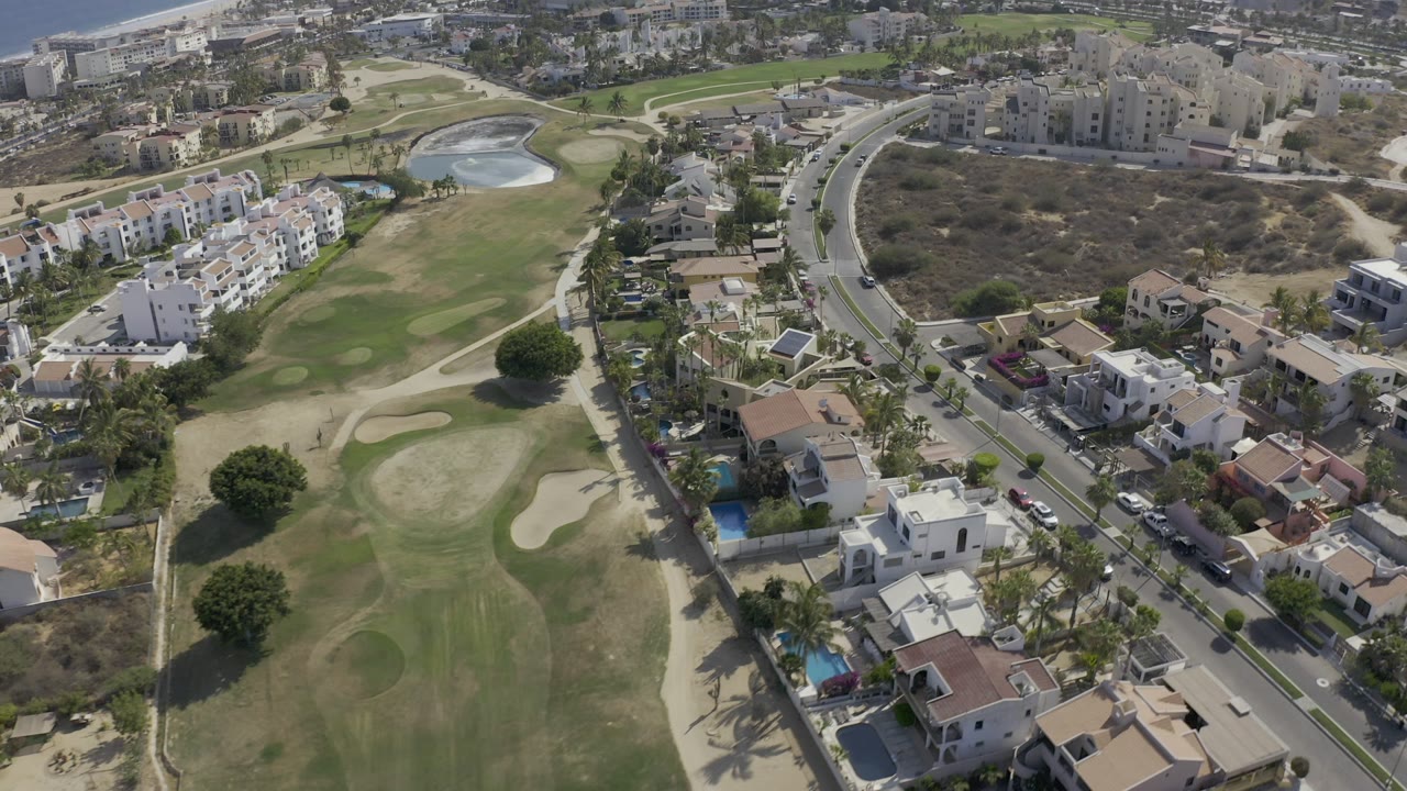Aerial view of golf course, homes, road, and pond