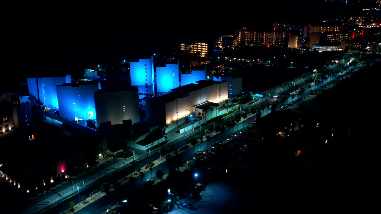 Night aerial over blue buildings and scattered city lights.