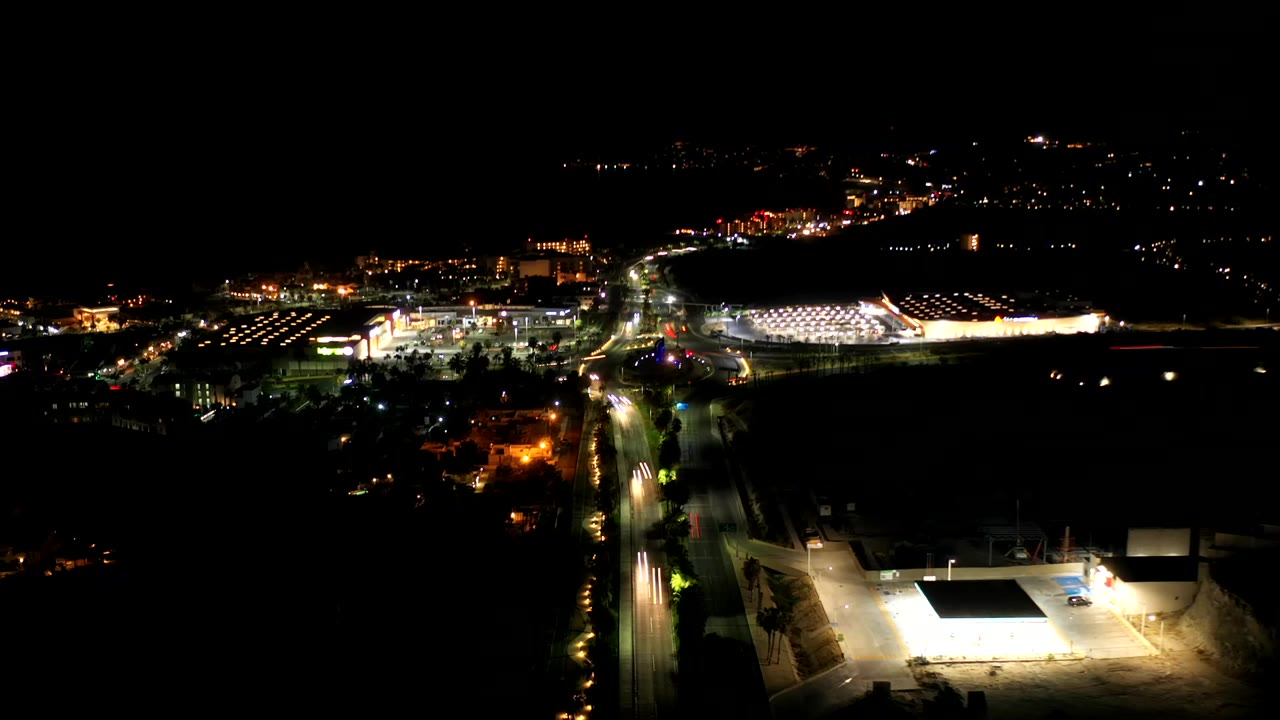Night aerial view of roads, bright buildings, and a lit roundabout