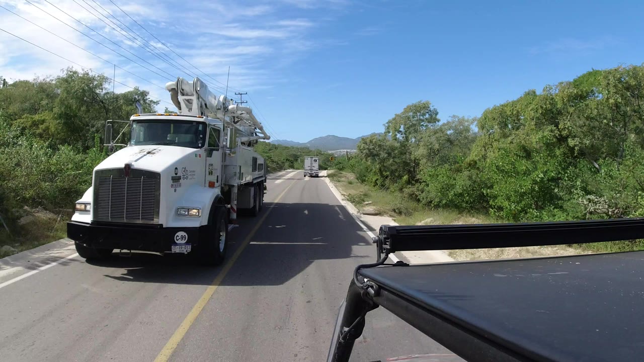 White utility truck passing beside a two-lane road