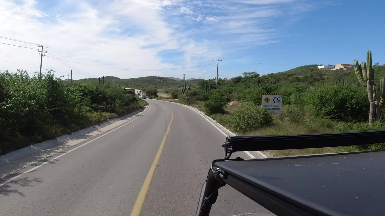 Two-lane road curving through desert shrubs under a blue sky