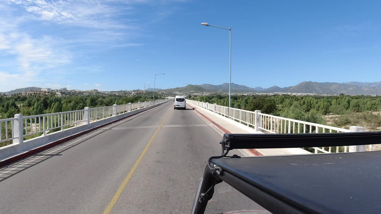 Forward view down an elevated two-lane bridge with a van ahead.