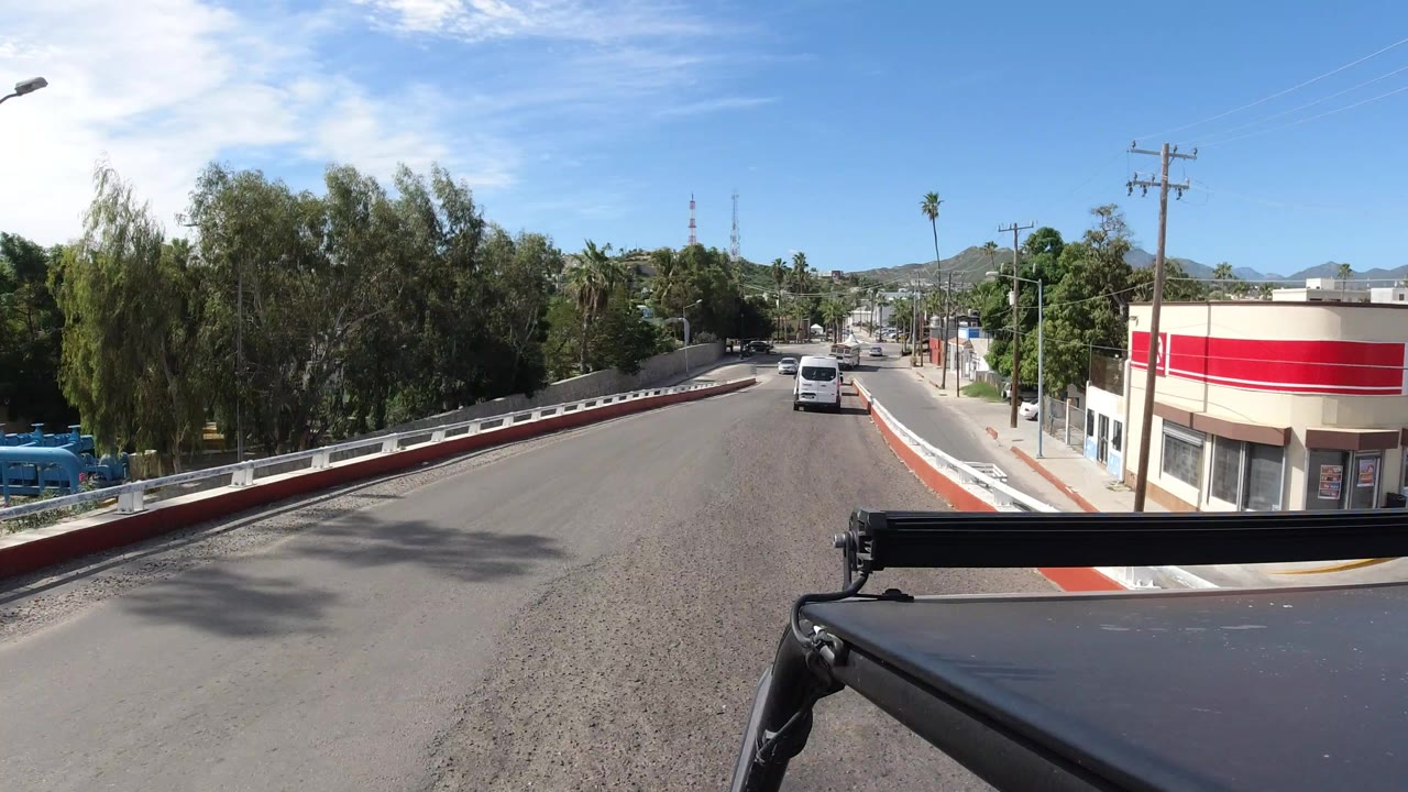 Forward road view with a white van ahead and trees along the street.