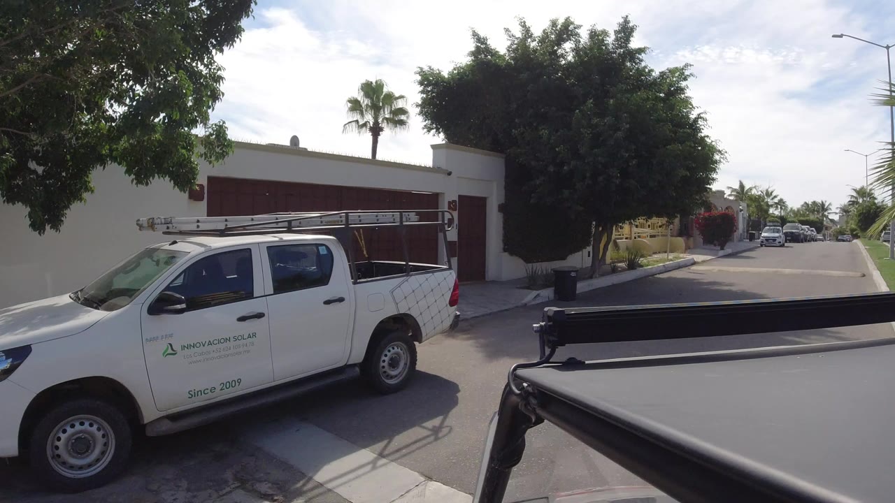 White service pickup beside a white-walled home on a quiet street.