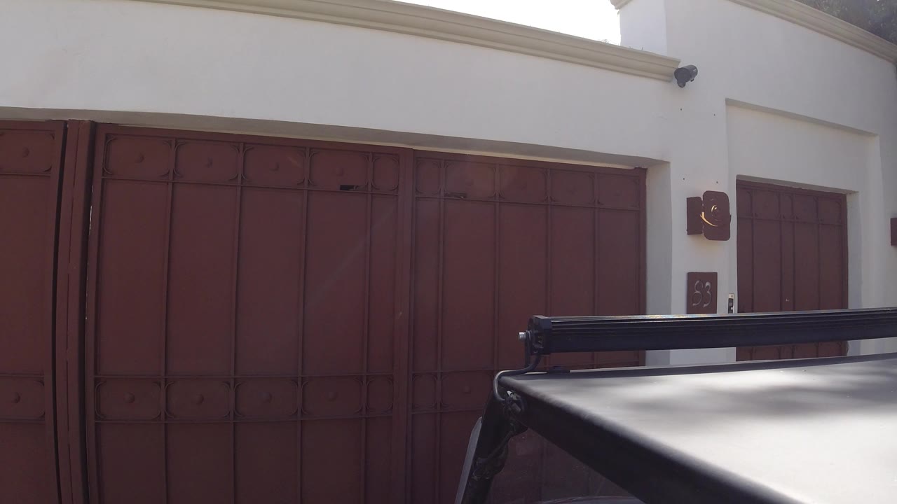Gray car roof in front of a red garage gate
