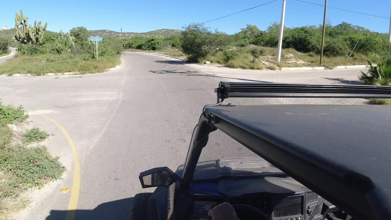 Off-road vehicle at a desert road junction with cacti and utility poles.