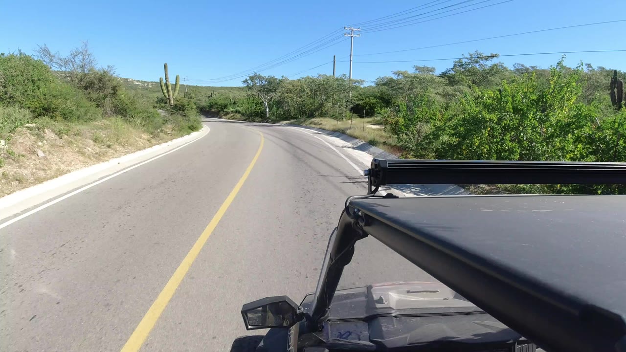 Curving paved road seen over the front of a black vehicle