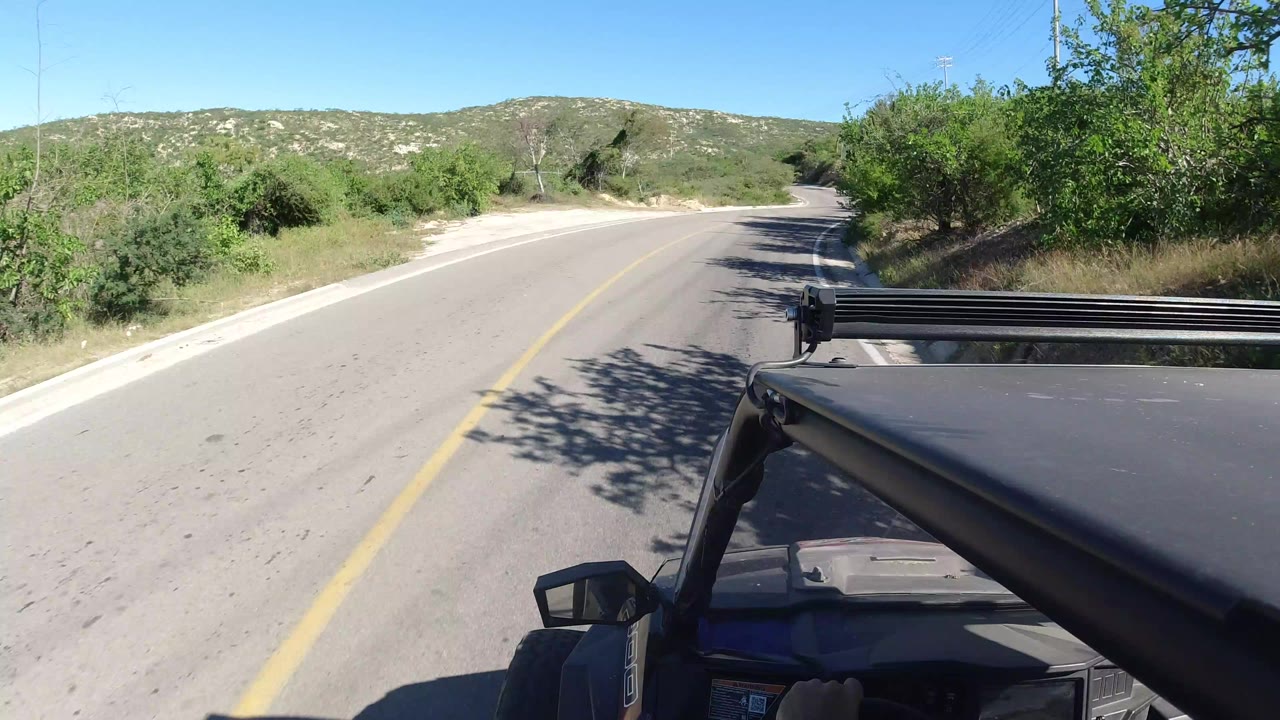 Forward road view from a vehicle on a sunny narrow road.
