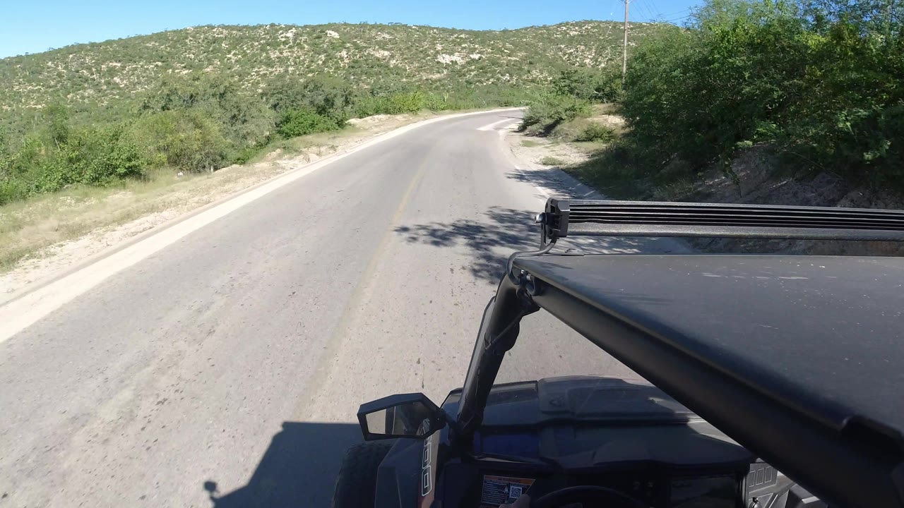Road bend with vehicle roof rack in bright sunlight.