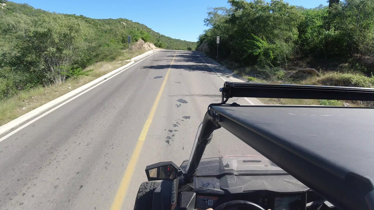 Curving paved road with brush and utility lines at right
