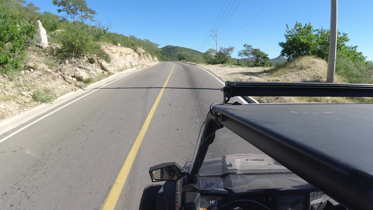 Vehicle-mounted view of empty road beside rocky slope