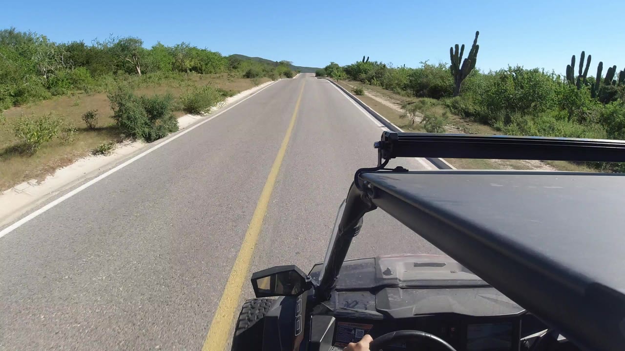 Forward view from a rugged vehicle on a straight desert road.
