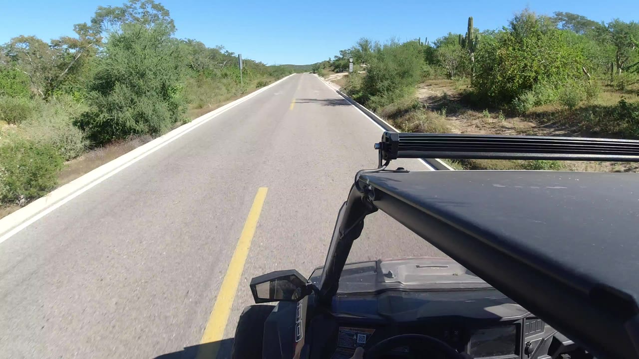Empty paved highway seen over a black Jeep hood and roof rack