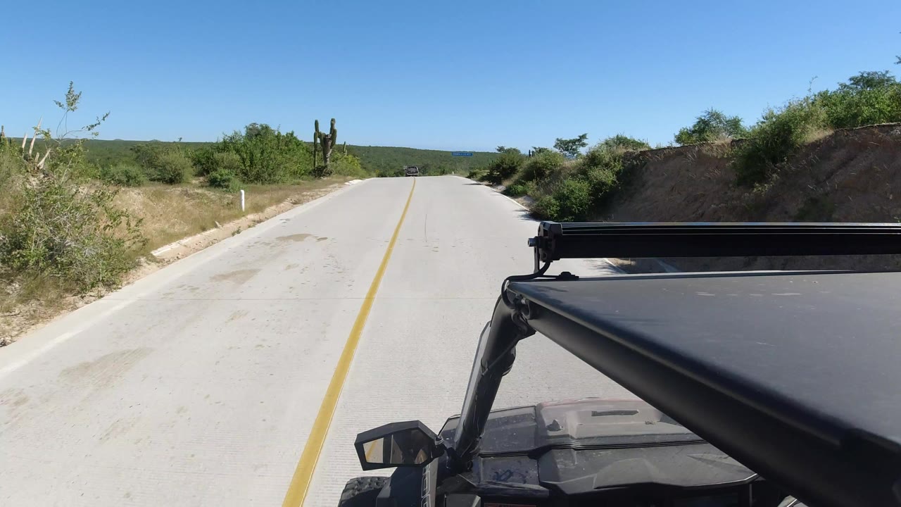 Paved road ahead with vehicle roof frame in the foreground